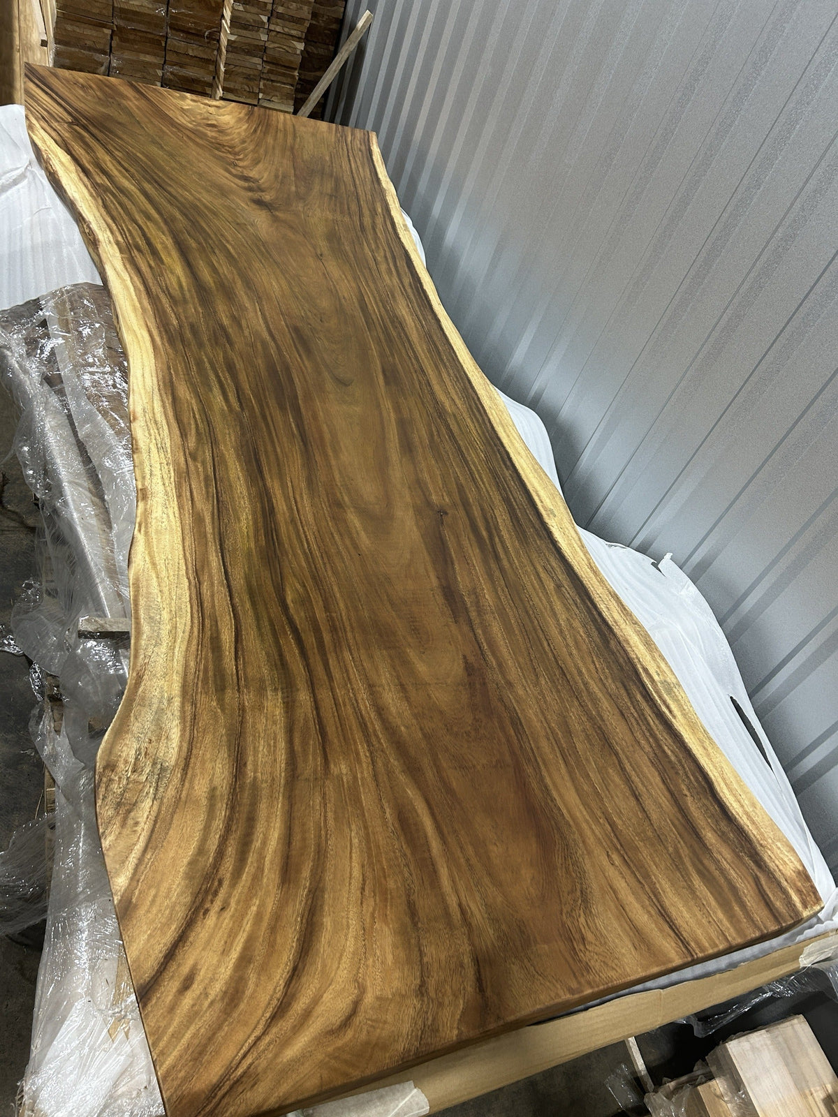 Slab No. 16, first face — the actual 9 ft single-slab Saman monkeypod top with uniform ribbon grain, matte lacquer finish, photographed in our Lincolnwood IL warehouse