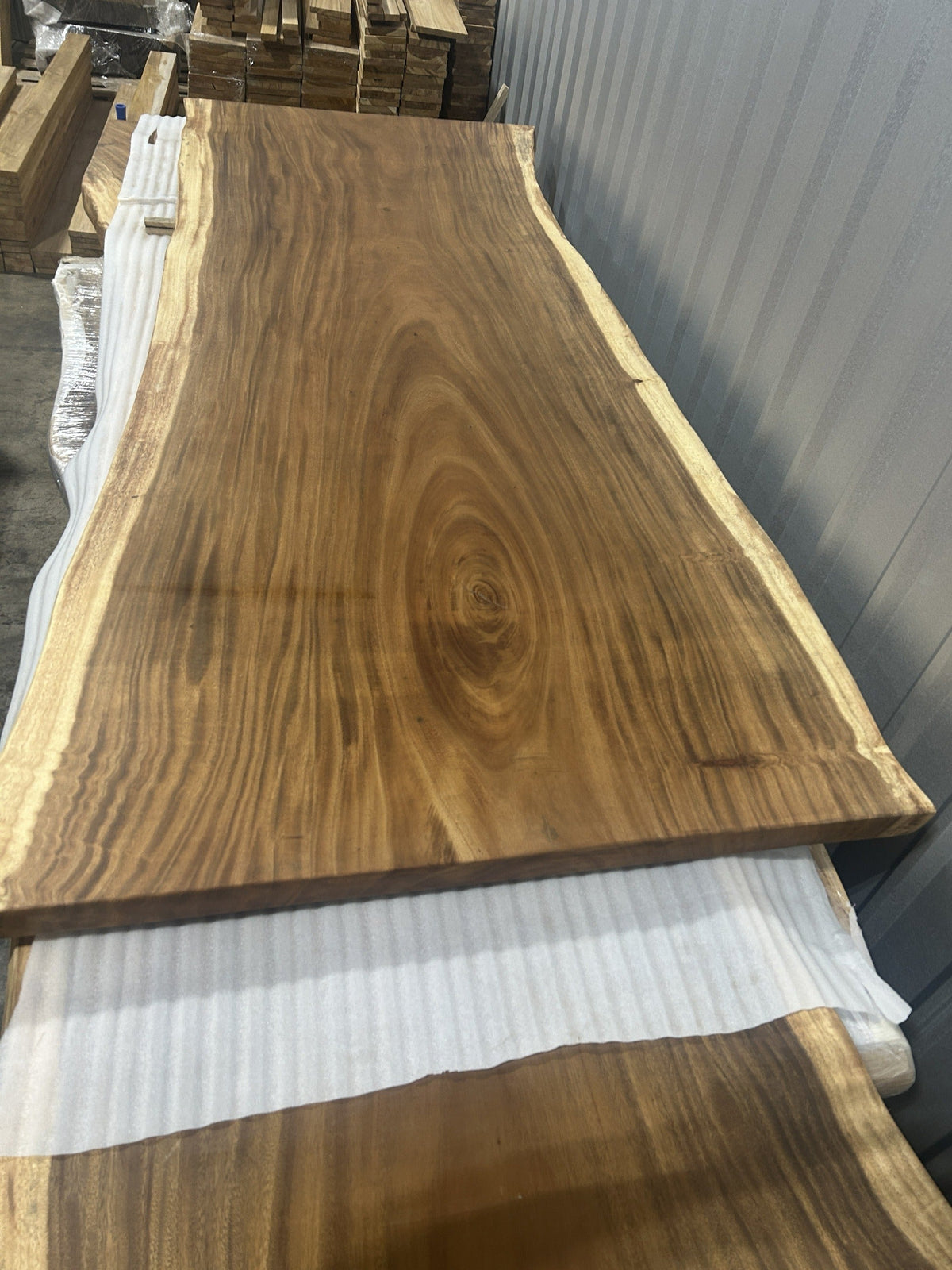Slab No. 19, opposite face — the actual 8 ft 4 in single-slab Saman monkeypod top with strong off-centre concentric figure, matte lacquer finish, Lincolnwood IL