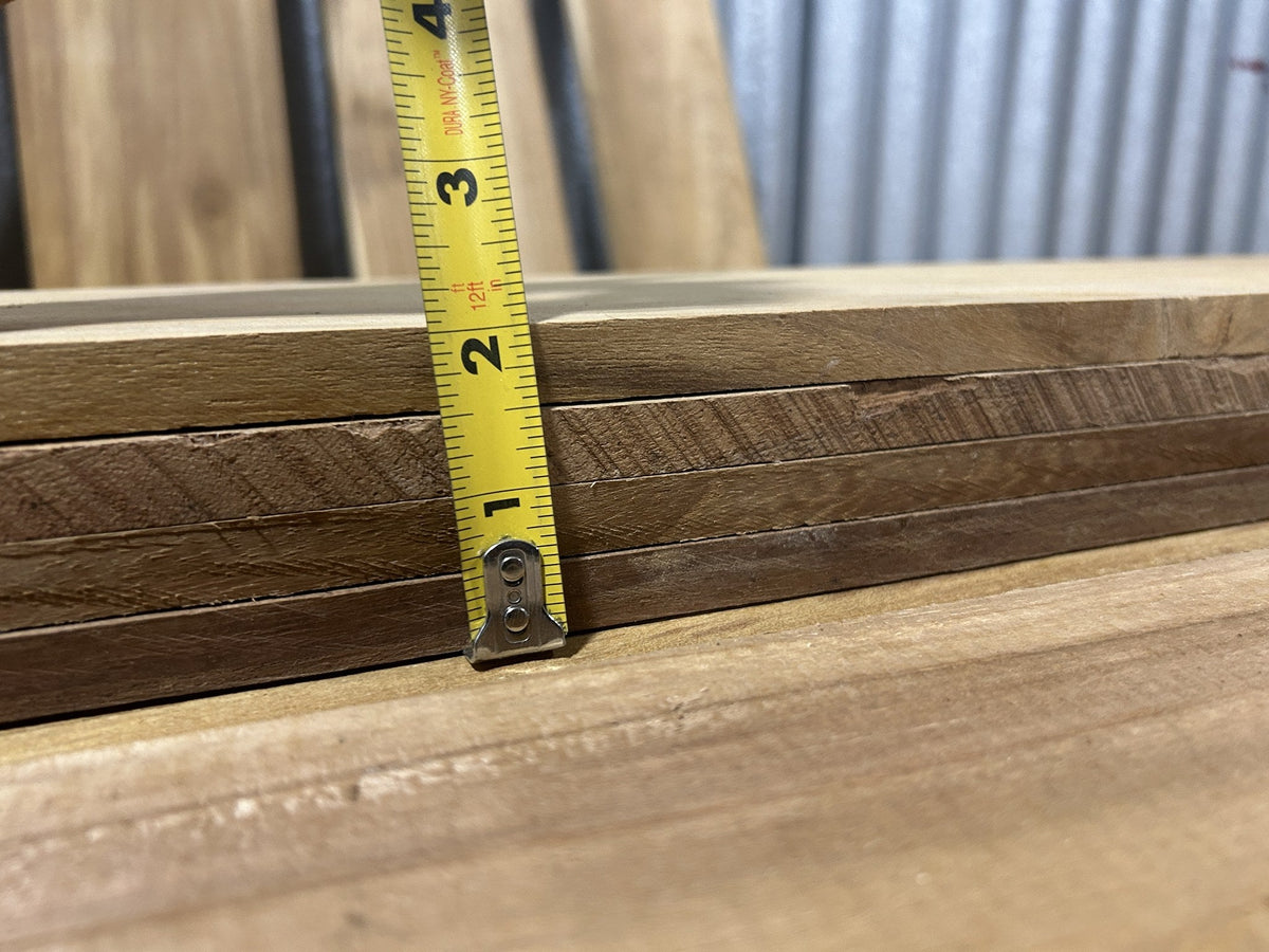 Tape measure held against the edge of a stack of Ecuadorian teak boards showing 3/4 in to 1 in thickness — actual inventory, Platinum Luxury Teak, Lincolnwood IL
